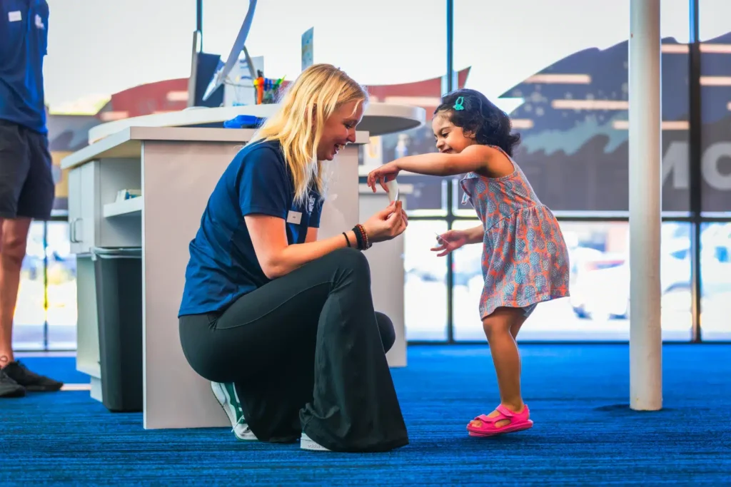 a staff member engaging with a young girl before her swim lesson