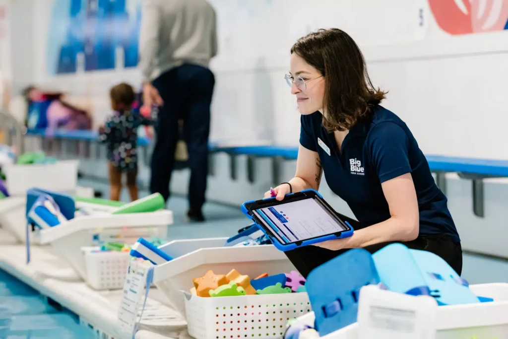 a staff member checking in on kids and swim tools during a lesson