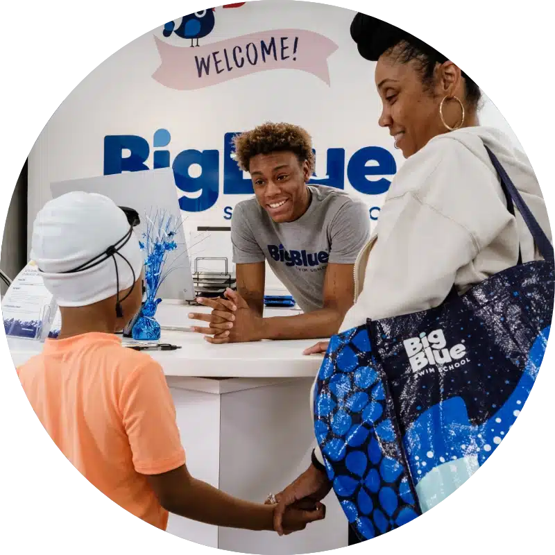front desk staff talking to and smiling with a new swimmer