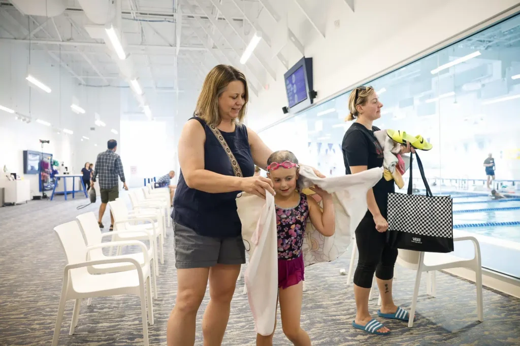 Mom wrapping her child in a towel after a swim lesson in the waiting room